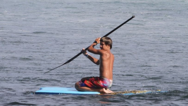 nino de rodillas practicando sup